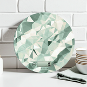 bilancia digitale da cucina con soggetto geometrico verde appoggiato su un piano da lavoro di una cucina moderna bianca