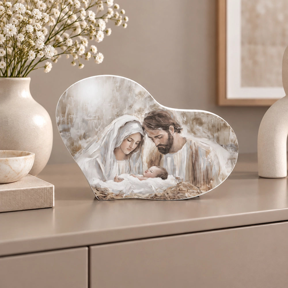Bomboniera Sacra Famiglia in stile pittorico, ambientata su mobile moderno laccato opaco con fiori bianchi e dettagli decorativi neutri.