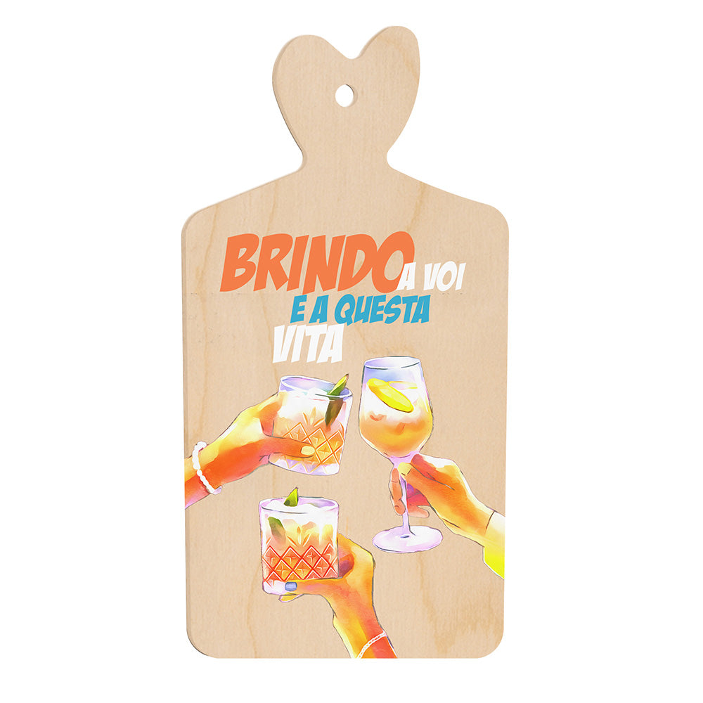 Tagliere in legno a forma di cuore con illustrazione di mani che brindano con bicchieri colorati e la frase “Brindo a voi e a questa vita” in stile vivace.