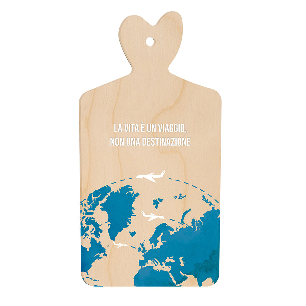 Tagliere in legno a forma di cuore con frase “La vita è un viaggio, non una destinazione” e illustrazione della mappa del mondo in blu con aerei bianchi in volo.