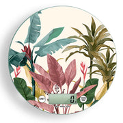 Bilancia digitale con decoro tropicale di foglie verdi, rosa e gialle, su sfondo chiaro, ispirazione botanica e naturale.