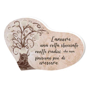 Bomboniera a cuore con albero della vita e scritta romantica ‘L’amore una volta sbocciato mette radici’, su sfondo beige con ornamenti floreali.