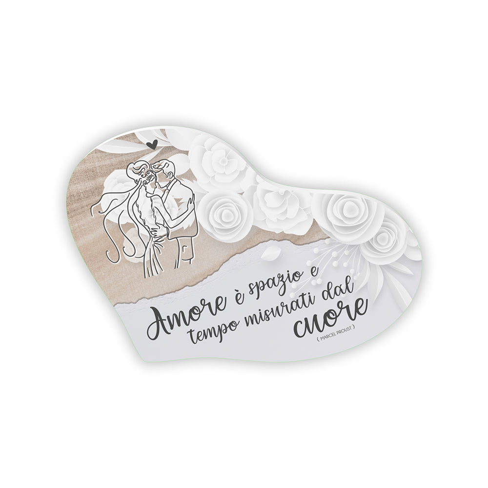 Bomboniera cuore matrimonio con sposi line art su sfondo lino beige, rose bianche e frase Marcel Proust "Amore è spazio e tempo misurati dal cuore"