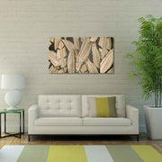 Quadro in plexiglass o vetro con eleganti foglie dorate su parete scura, montato sopra divano chiaro in salotto moderno.