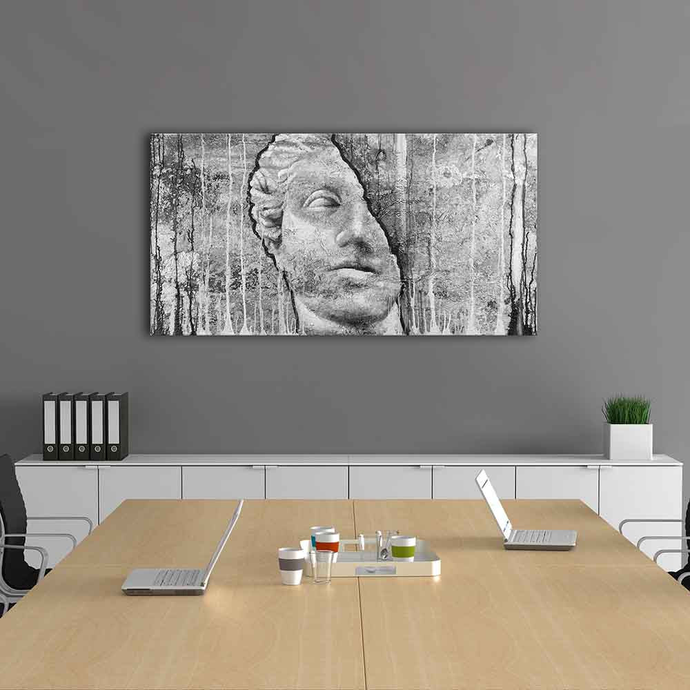 Quadro in plexiglass o vetro con volto scolpito dall’aria enigmatica su parete materica, installato in sala riunioni dal design moderno.