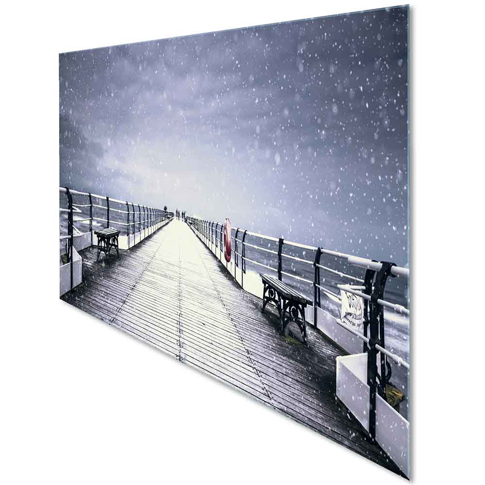 Vista laterale di un quadro in plexiglass o vetro con paesaggio di un pontile nel periodo invernale, fiocchi di neve cadono dal cielo.