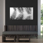 Quadro in plexiglass o vetro con foglie di palma riflesse nell'acqua, appeso su parete scura in soggiorno moderno dai toni naturali.