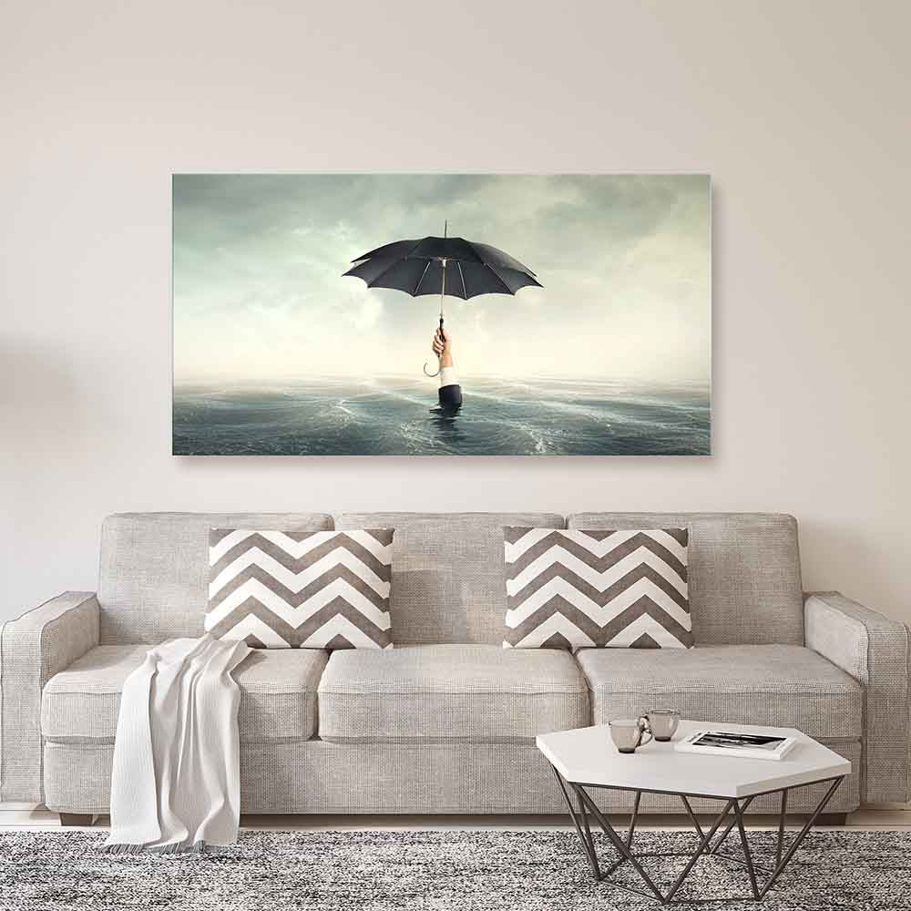 Quadro in plexiglass o vetro con mano che emerge dall'acqua reggendo un ombrello, su parete chiara sopra divano moderno beige.