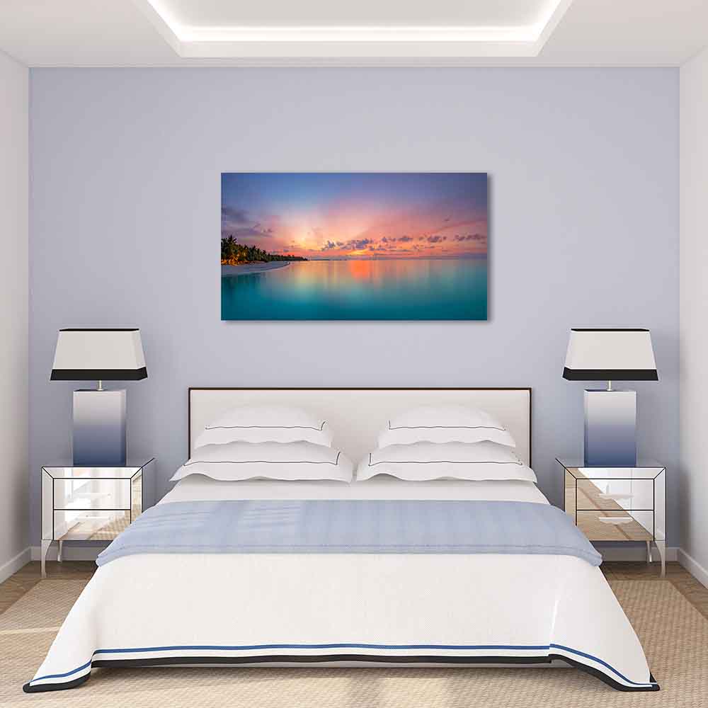 Quadro in plexiglass o vetro con spiaggia tropicale al tramonto, cielo rosato e mare calmo turchese, posizionato sopra un letto in una camera.