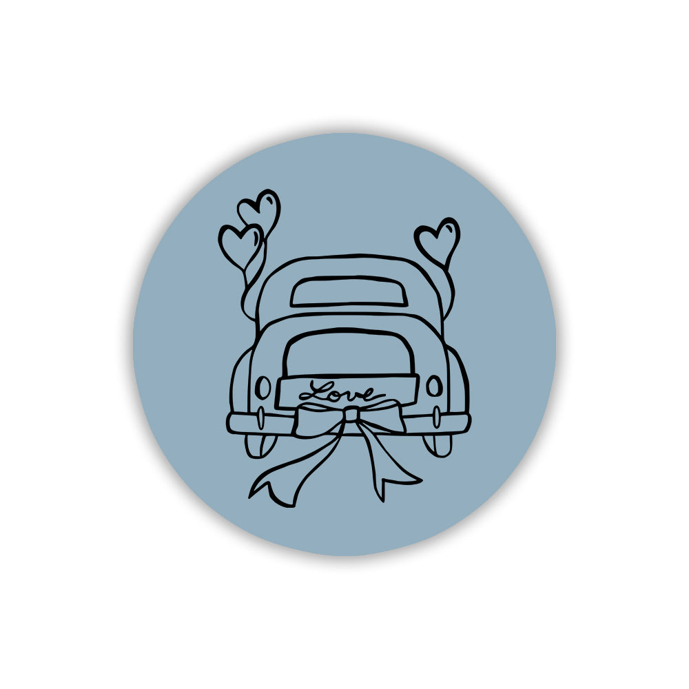 Magnete circolare azzurro polvere con illustrazione nera di macchina nuziale, cuori volanti e fiocco decorativo. Idea regalo per invitati.