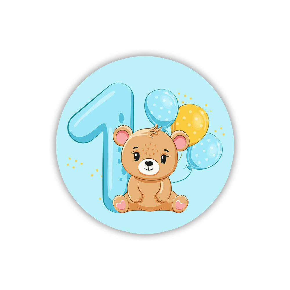 Calamita tonda azzurra per 1° compleanno bimbo con orsetto seduto, palloncini celesti e gialli a pois e numero uno grande.