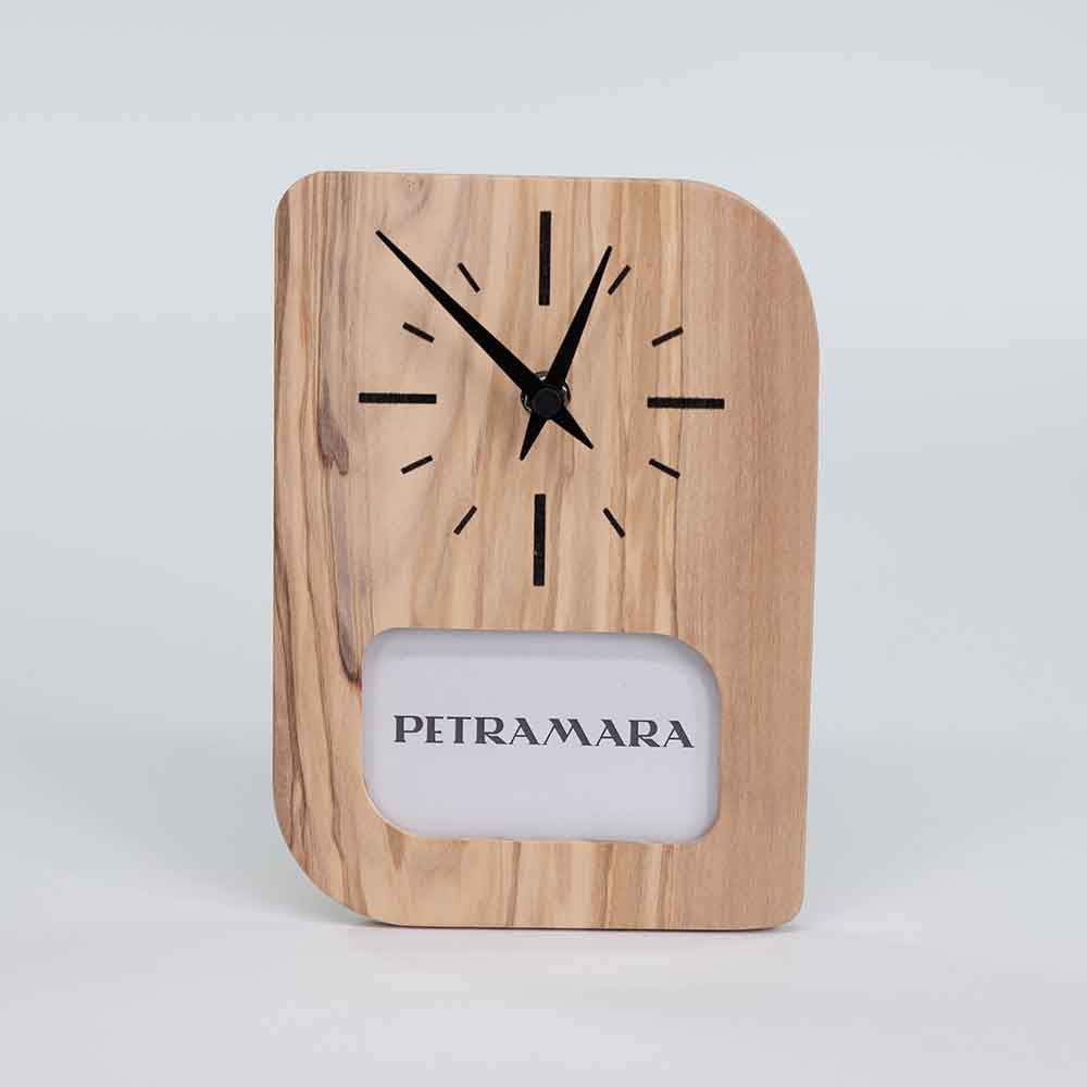 Orologio portafoto in ulivo con cornice per foto integrata, posizionato su un tavolo, evidenziando le venature naturali del legno.