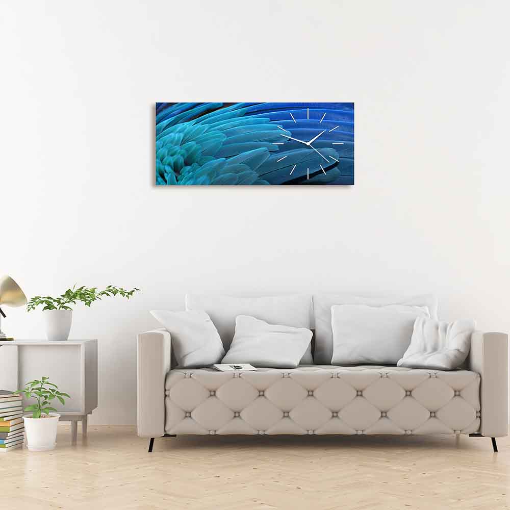 Orologio in plexiglass con decorazione di piume blu leggere e delicate, posizionato sopra un divano in un ambiente accogliente.