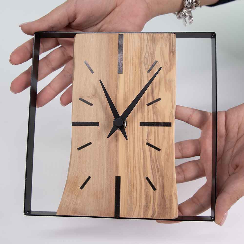 Orologio ulivo acciaio da tavolo tenuto tra le mani, evidenziando dimensioni e lavorazione artigianale.