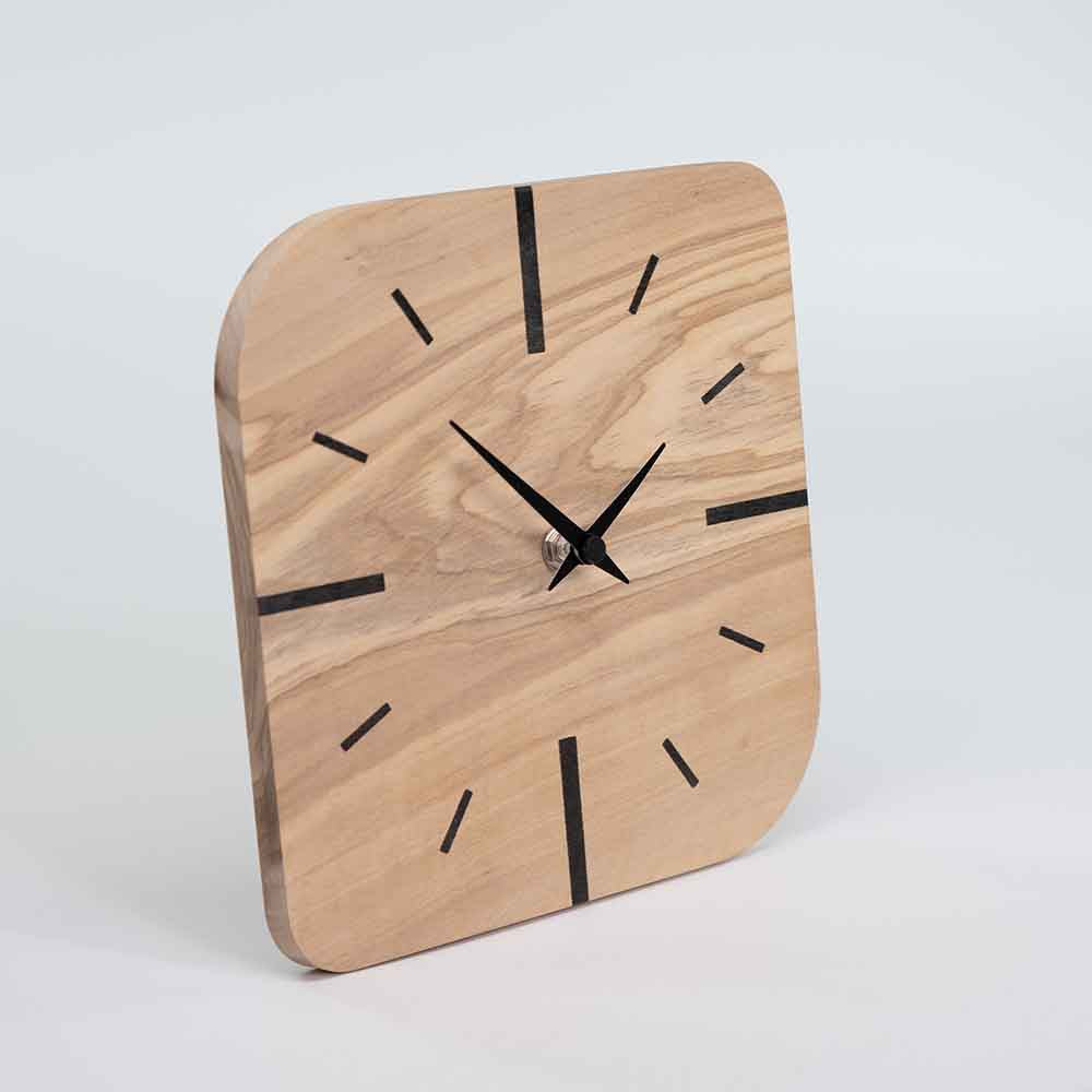 Vista laterale di un orologio in ulivo da tavolo dal profilo sottile, con struttura solida e finitura liscia che valorizza il legno naturale.