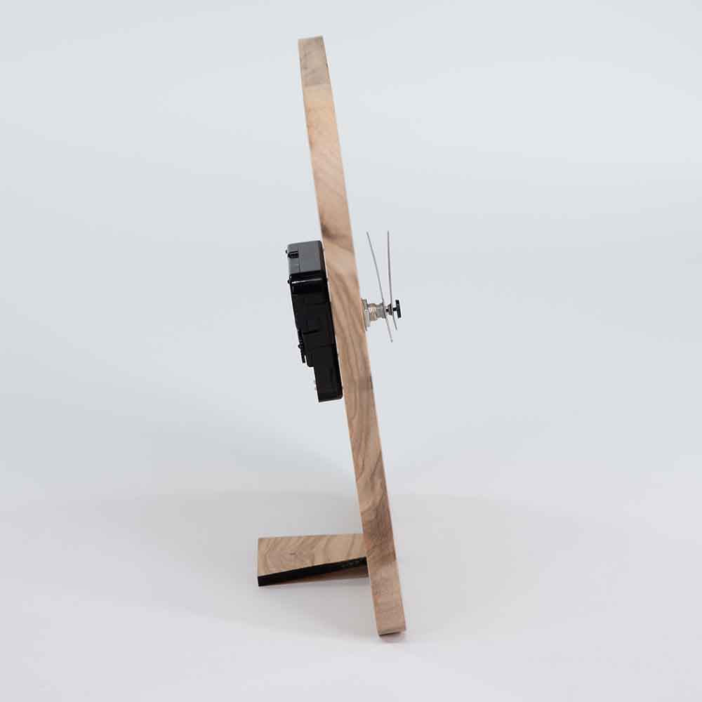 Orologio in ulivo da tavolo visto di lato, con forma essenziale e dettagli in legno che esaltano l'eleganza del materiale naturale.