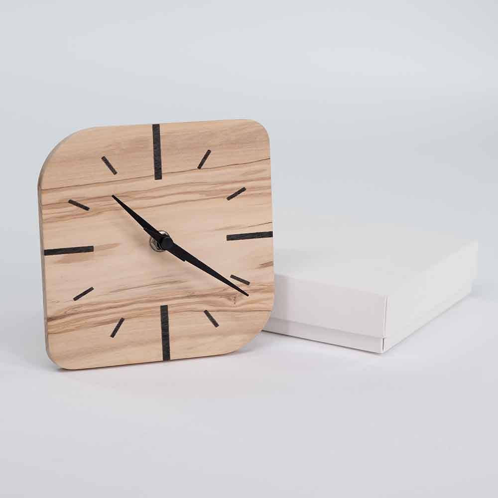 Orologio in ulivo da tavolo piccolo fiancheggiato dalla sua confezione, perfetto come regalo con un design minimalista e raffinato.