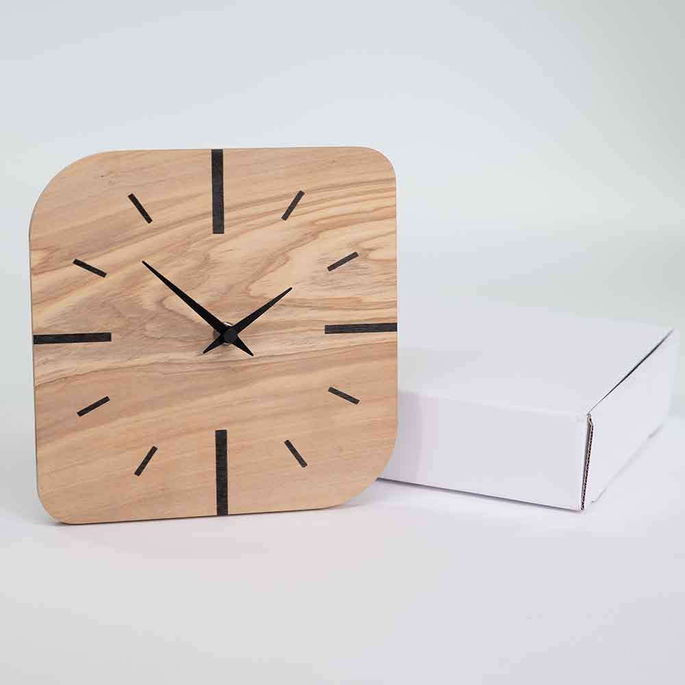 Orologio in ulivo da tavolo quadrato accostato al suo imballo, ideale come complemento d'arredo elegante e artigianale.
