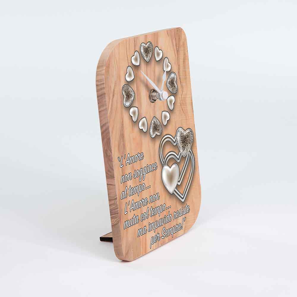Vista laterale di un orologio in ulivo da tavolo con decoro di cuori, evidenziando la profondità del disegno e la struttura del legno.
