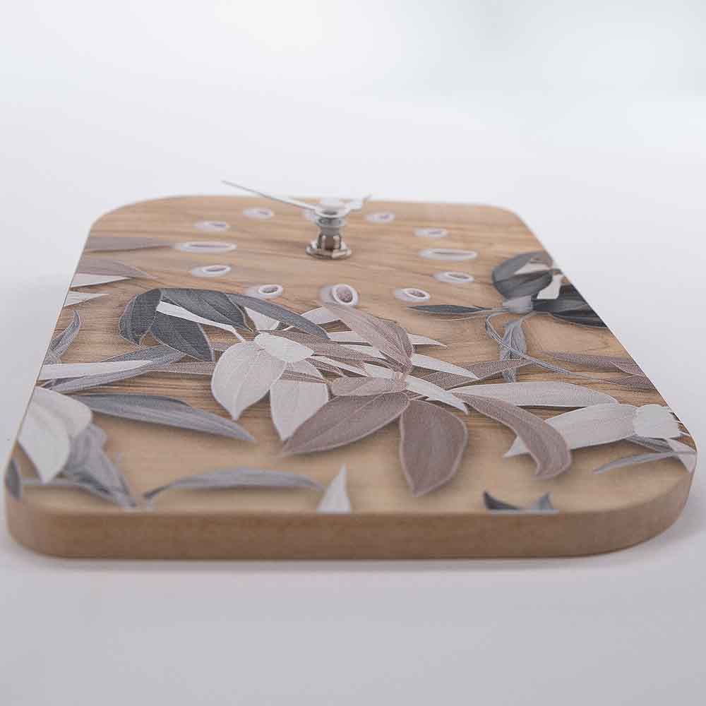 Orologio in ulivo da tavolo con decorazione di foglie stilizzate, visto dal basso per un dettaglio armonioso e naturale.