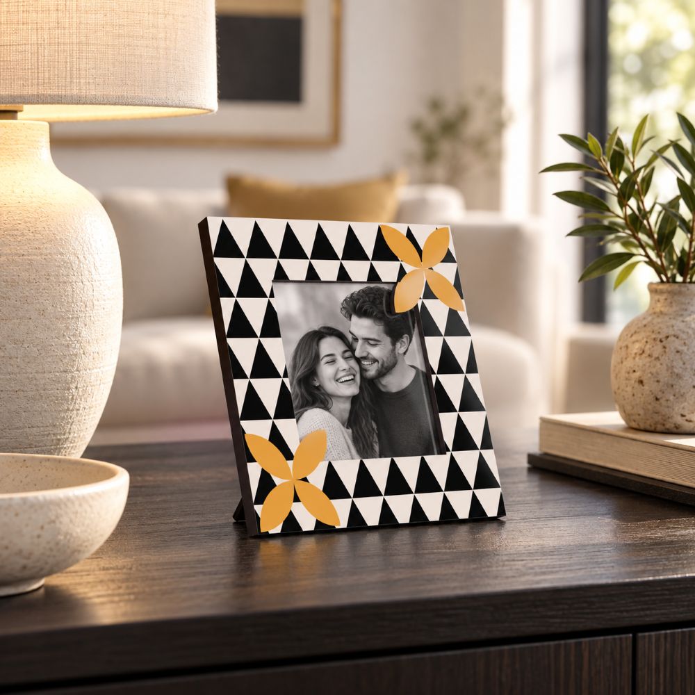 Portafoto decoro geometrico Black 15×15 cm con foto di coppia, ambientato su una madia scura in un soggiorno moderno.