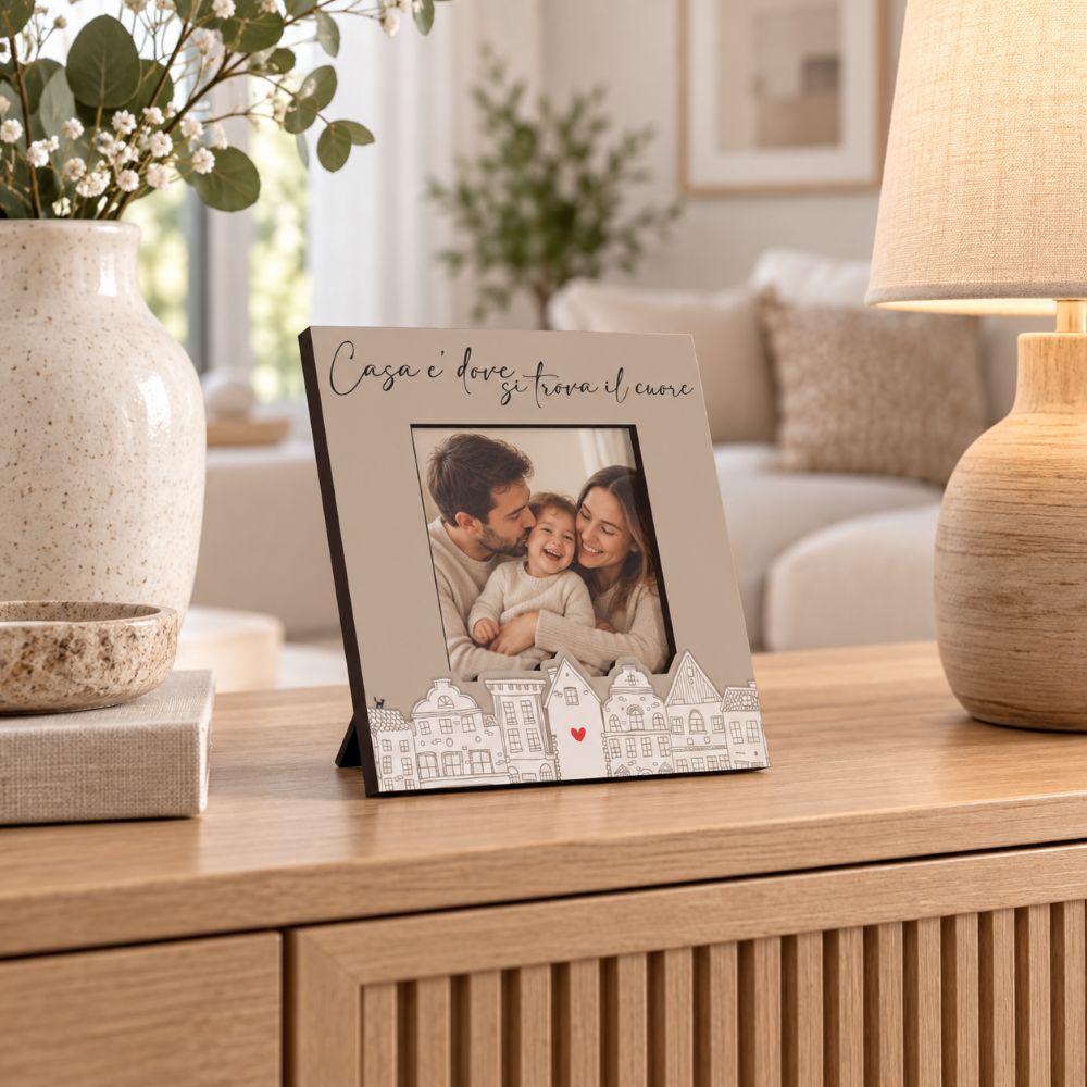 Portafoto con frase Home Cuore 15×15 cm con foto di famiglia, ambientato su una madia in legno in un soggiorno dai toni naturali