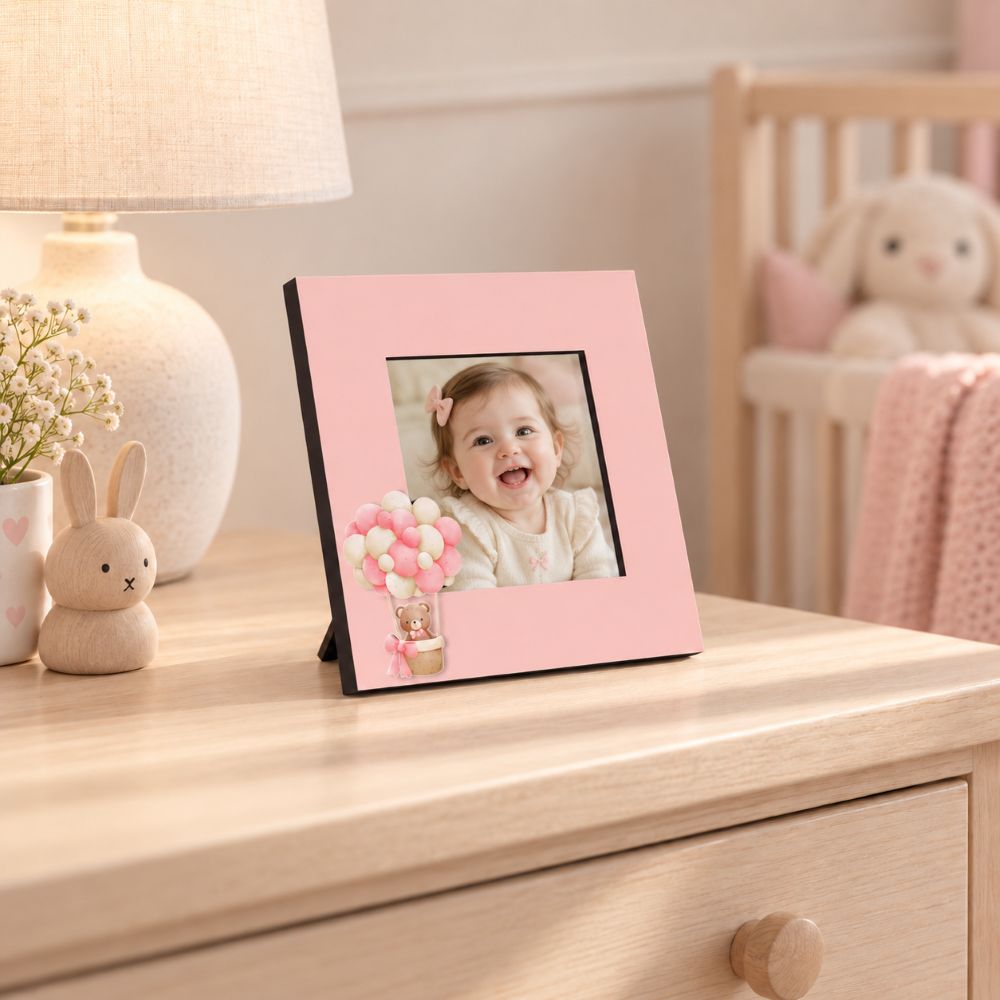 Portafoto rosa Teddy Balloon da 15×15 cm con foto di una bambina, ambientato su una cassettiera in cameretta