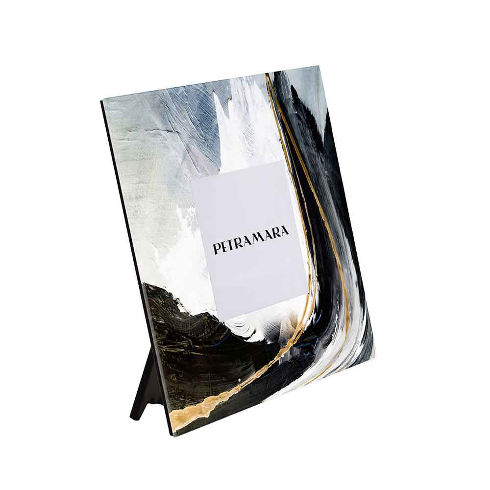 Vista laterale di un portafoto in vetro quadrato il decoro richiama l’effetto della pennellata, con toni neri, bianchi e dorati dal design moderno.