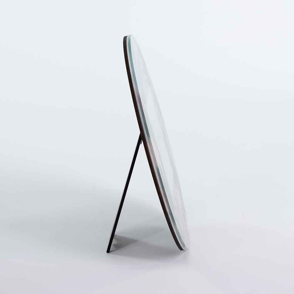 Vista laterale di un portafoto vetro rotondo, evidenziando lo spessore del materiale e il supporto posteriore.