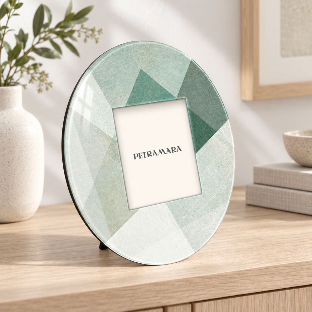 Portafoto rotondo in vetro con decoro geometrico verde Shapes, ambientato su una madia in legno chiaro dal design moderno