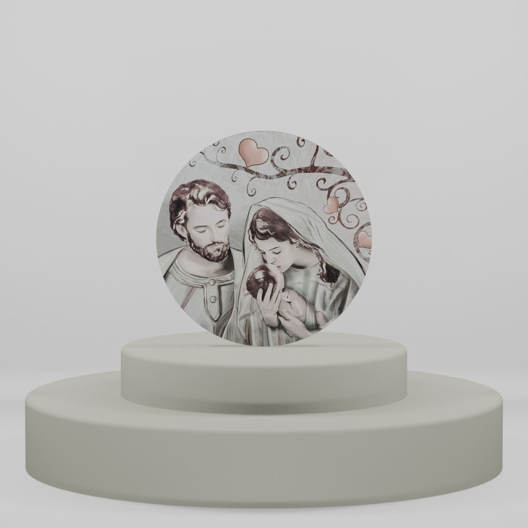 Carica video: Magnete in legno circolare con illustrazione della Sacra Famiglia sotto rami decorati con cuori, ideale come bomboniera religiosa o regalo natalizio.