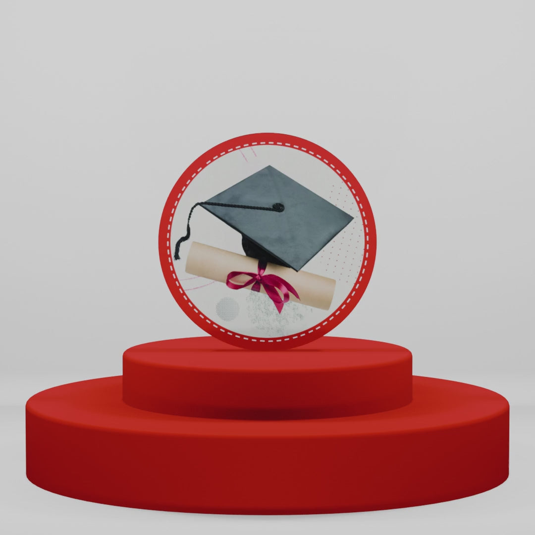 Carica video: Magnete tondo in legno per laurea con tocco nero e diploma con nastro rosso. Idea regalo o bomboniera celebrativa su piedistallo rosso intenso.