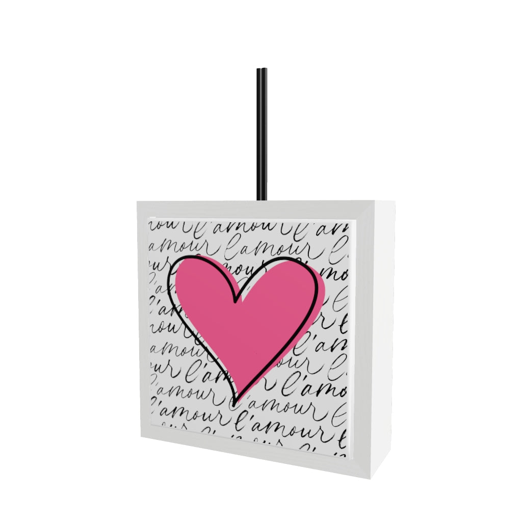 Modello 3D profumatore ceramica bianco con piastrella cuore rosa fucsia e scritta "l'amour" ripetuta in corsivo nero su sfondo bianco, bastoncini reed neri