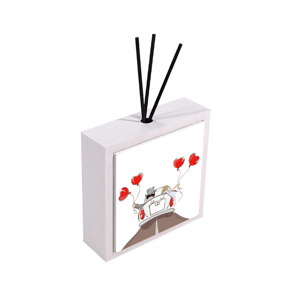 Profumatore ceramica bianco vista laterale, piastrella con sposi in auto bianca decappottabile di schiena, palloncini rossi a cuore, sfondo bianco, reed neri