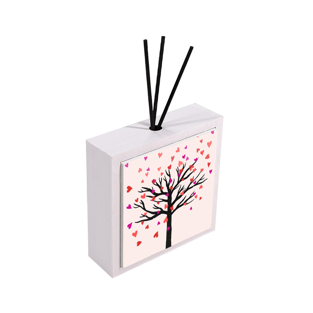 Profumatore ceramica bianco vista laterale, albero nero con cuori cadenti in rosa, rosso e viola su sfondo rosa pallido, idea bomboniera, reed neri