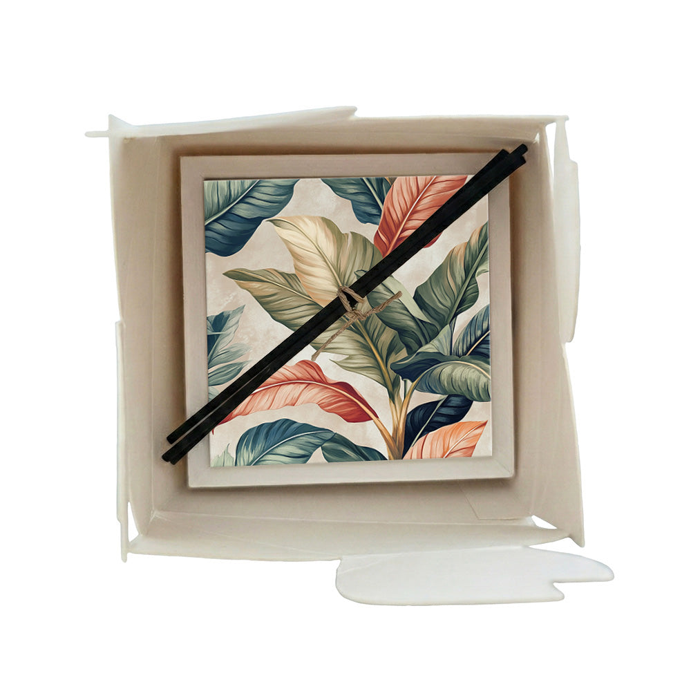 Profumatore ceramica in scatola con foglie tropicali botaniche in verde teal, corallo e crema su sfondo beige chiaro, bastoncini reed neri in confezione regalo
