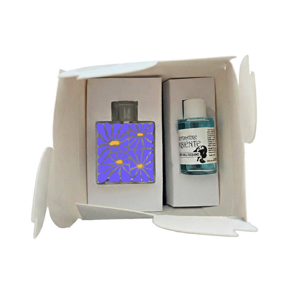 Kit profumatore vetro in scatola bianca, boccetta con quattro margherite blu pervinca e centri arancio, flacone fragranza Vento dell'Oceano incluso, reed neri