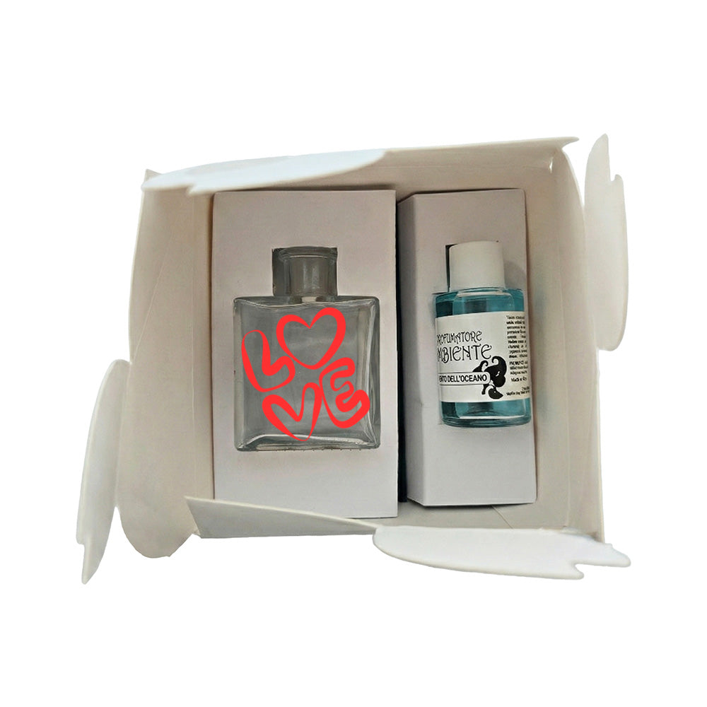 Kit profumatore vetro in scatola bianca, flacone con scritta LOVE rossa a tratto arrotondato e cuore rosso, fragranza Vento dell’Oceano inclusa, reed neri