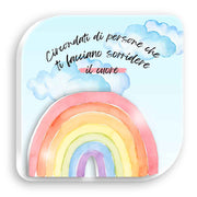 Quadretto in legno con arcobaleno multicolore in rilievo su sfondo con nuvole e scritta “Circondati di persone che ti fanno sorridere il cuore”.