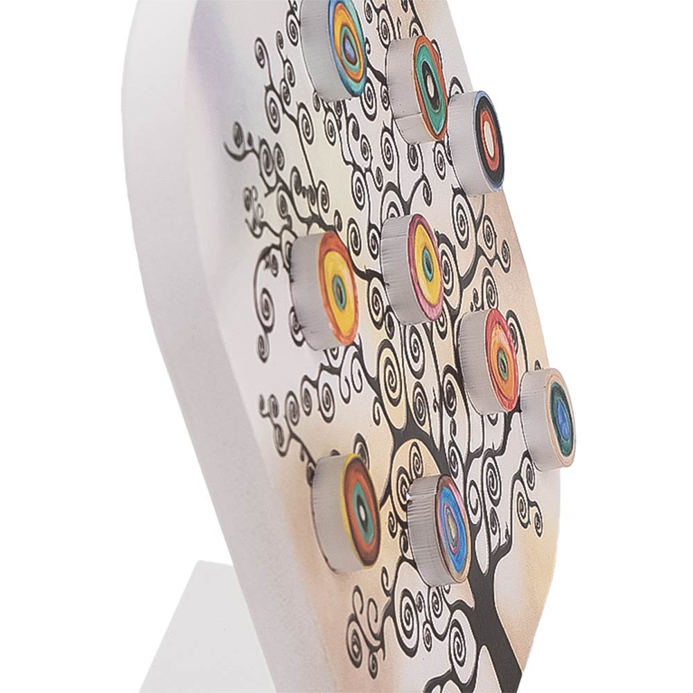 Dettaglio ravvicinato del quadretto in legno con albero nero e decorazioni circolari multicolore in rilievo su sfondo sfumato chiaro.