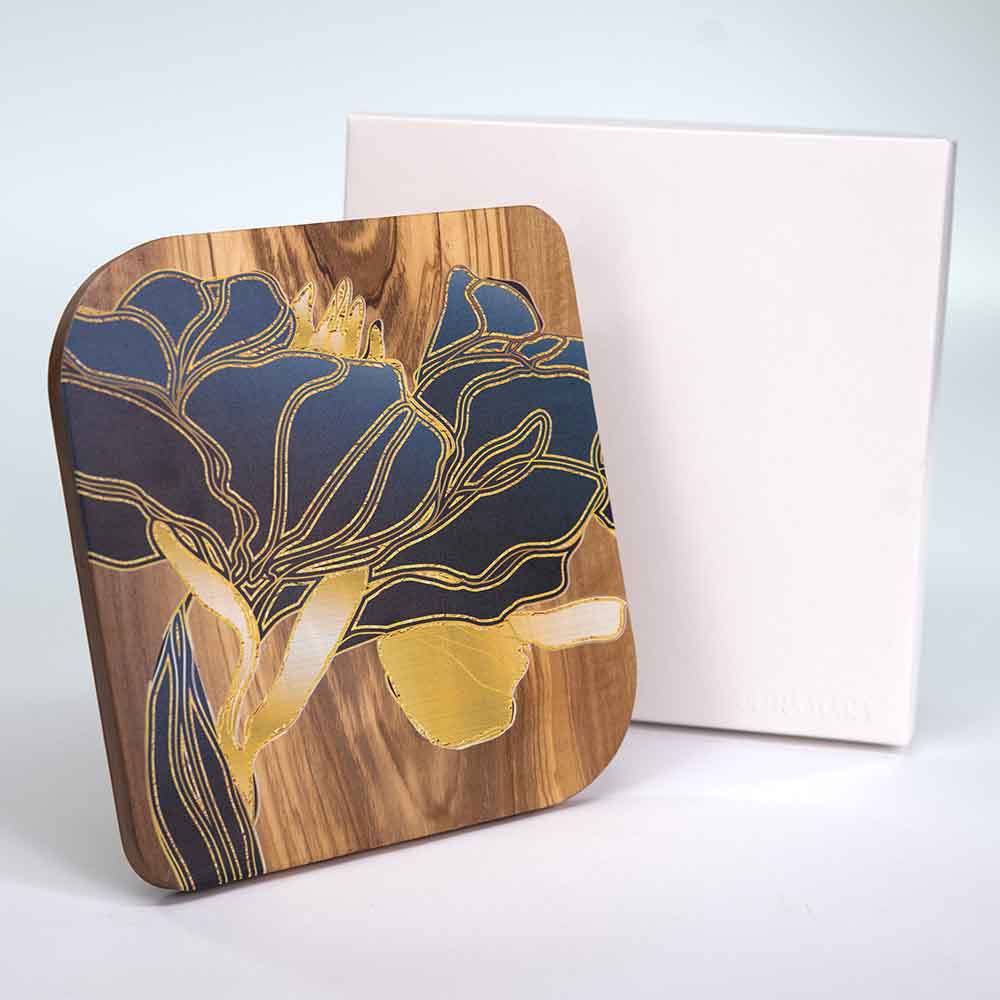 Quadretto in legno d'ulivo con decorazione floreale dorata, presentato al fianco della sua scatola in posizione verticale.
