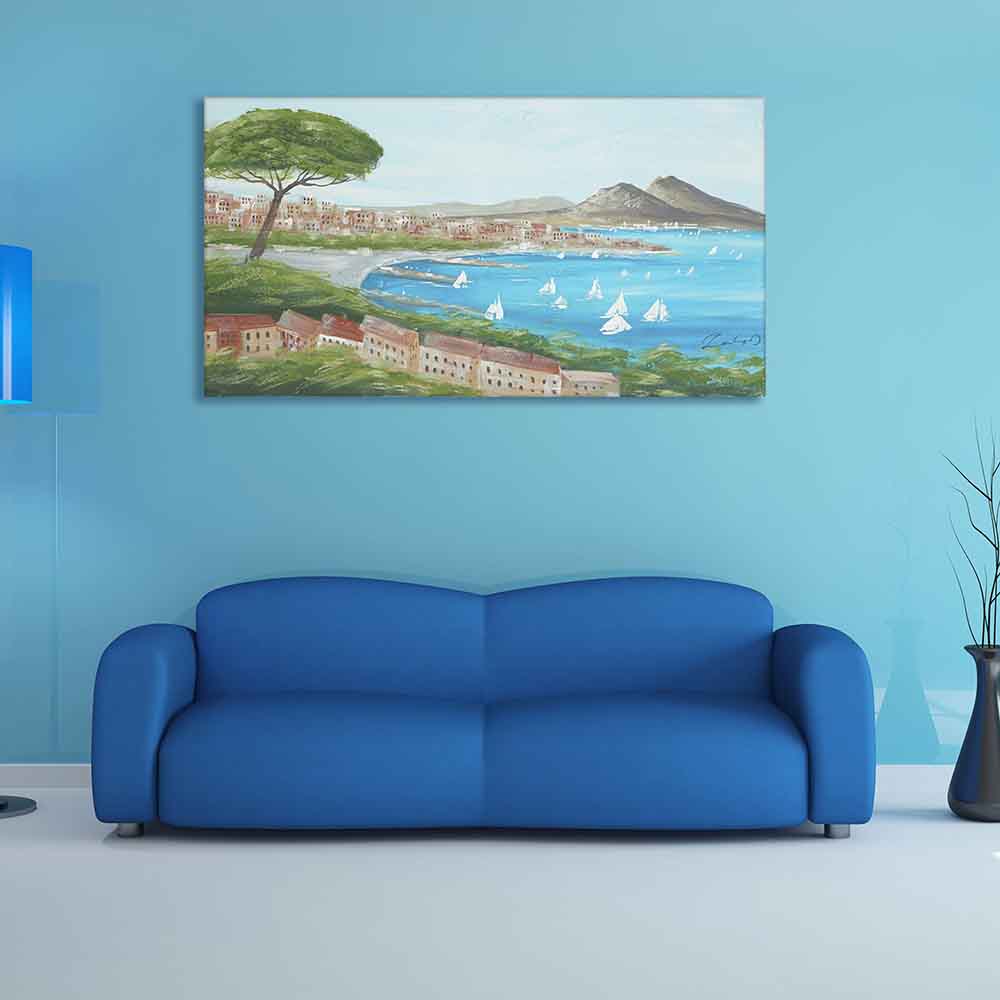 Quadro dipinto a mano con panorama del Golfo di Napoli, cielo azzurro e barche a vela, appeso sopra un divano blu in ambiente moderno.
