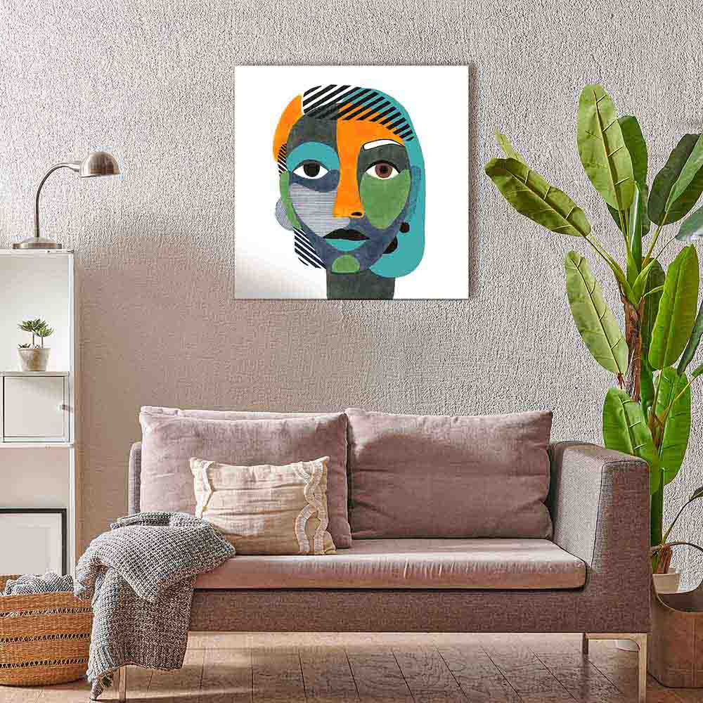Quadro su tela con ritratto femminile geometrico in toni vivaci su fondo bianco, appeso sopra un divano beige in un salotto moderno con piante verdi.