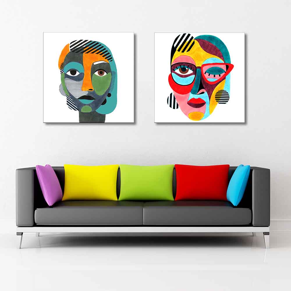 Coppia di quadri su tela con ritratti femminili astratti in stile pop, con forme colorate e motivi a righe su sfondo bianco, sopra divano multicolor.