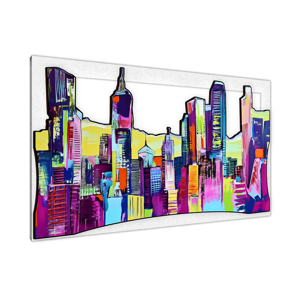 Quadro in legno intagliato vista laterale: pannello 3D con skyline urbano di grattacieli vivaci, colori neon e profili neri, cornice bianca