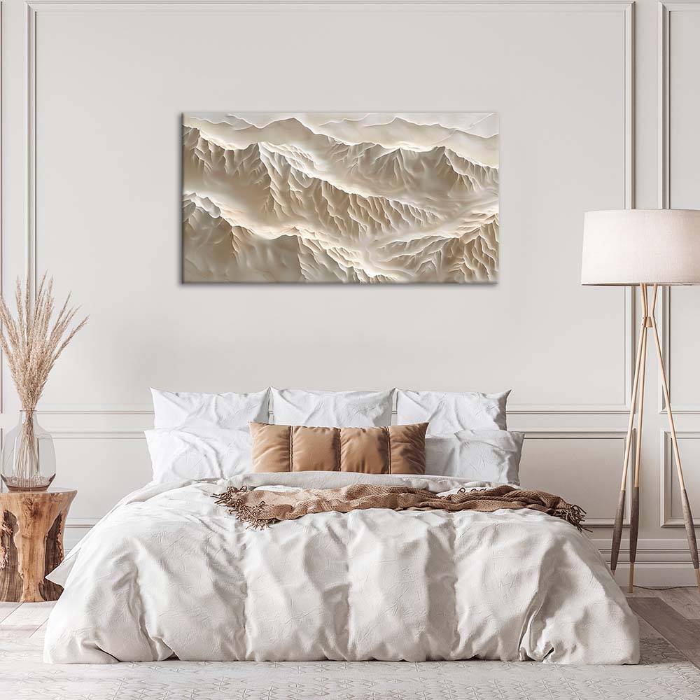 Quadro materico beige con rilievi a strati effetto montagne, appeso centrato sopra letto in camera da letto neutra con lampada e cuscini chiari.