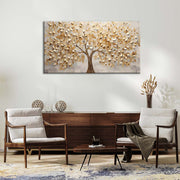 Quadro materico con albero dalle foglie dorate in rilievo, appeso su parete chiara sopra credenza in legno in soggiorno con poltrone e tavolino.