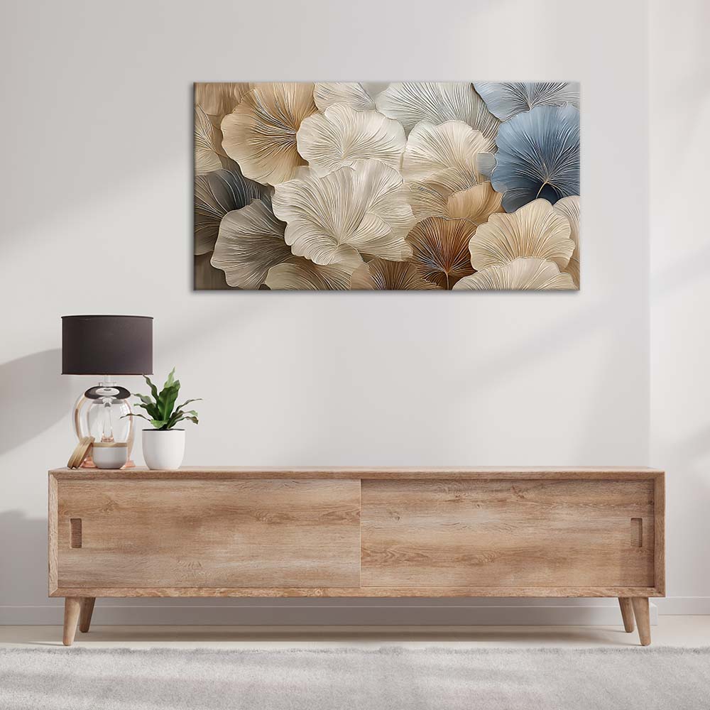 Quadro materico con grandi petali a ventaglio in toni crema e blu polvere, appeso sopra mobile in legno in soggiorno minimal con lampada e pianta.