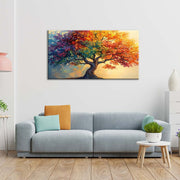 Quadro materico con albero a chioma arcobaleno e tronco tortuoso, appeso centrato sopra divano grigio in soggiorno luminoso con cuscini colorati.