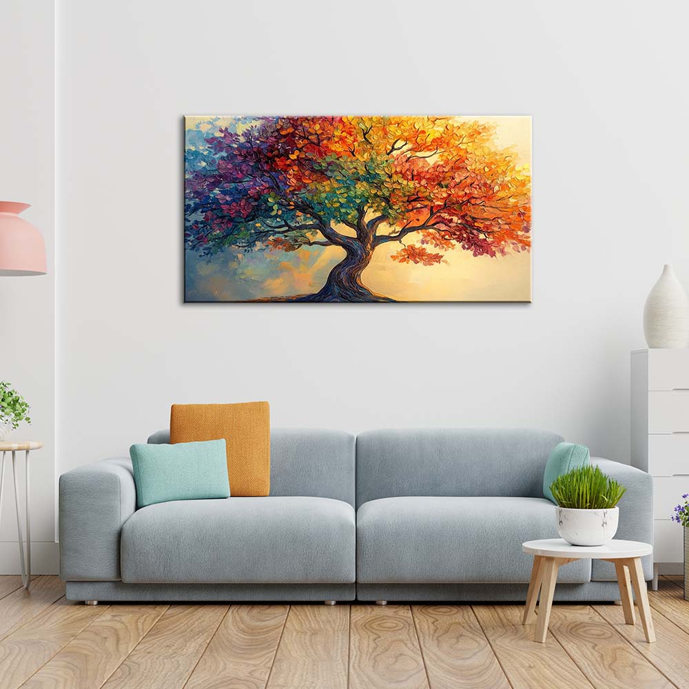 Quadro materico con albero a chioma arcobaleno e tronco tortuoso, appeso centrato sopra divano grigio in soggiorno luminoso con cuscini colorati.